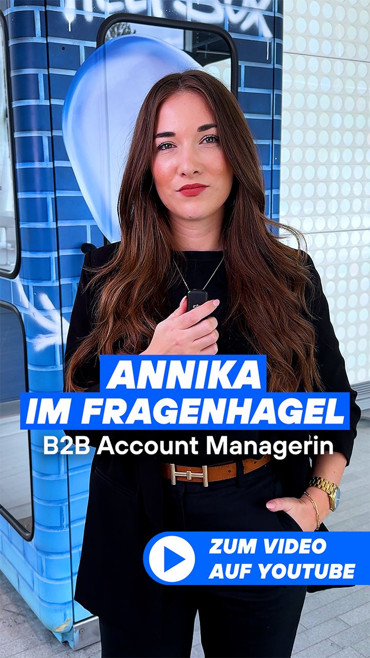 Annika steht mit Mikrofon in der Münchner Lobby vor der Telefonzelle