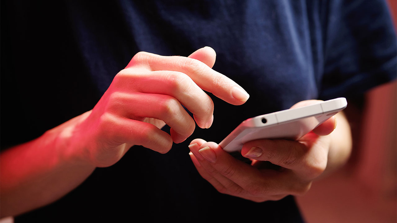 Person hält Smartphone in rötlichem Licht.