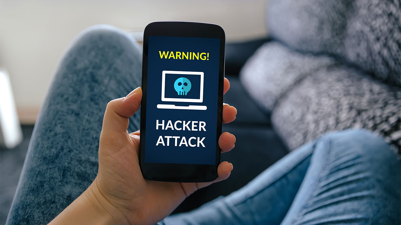 Person hält ein Handy mit einer Hackerangriffswarnung auf dem Bildschirm.