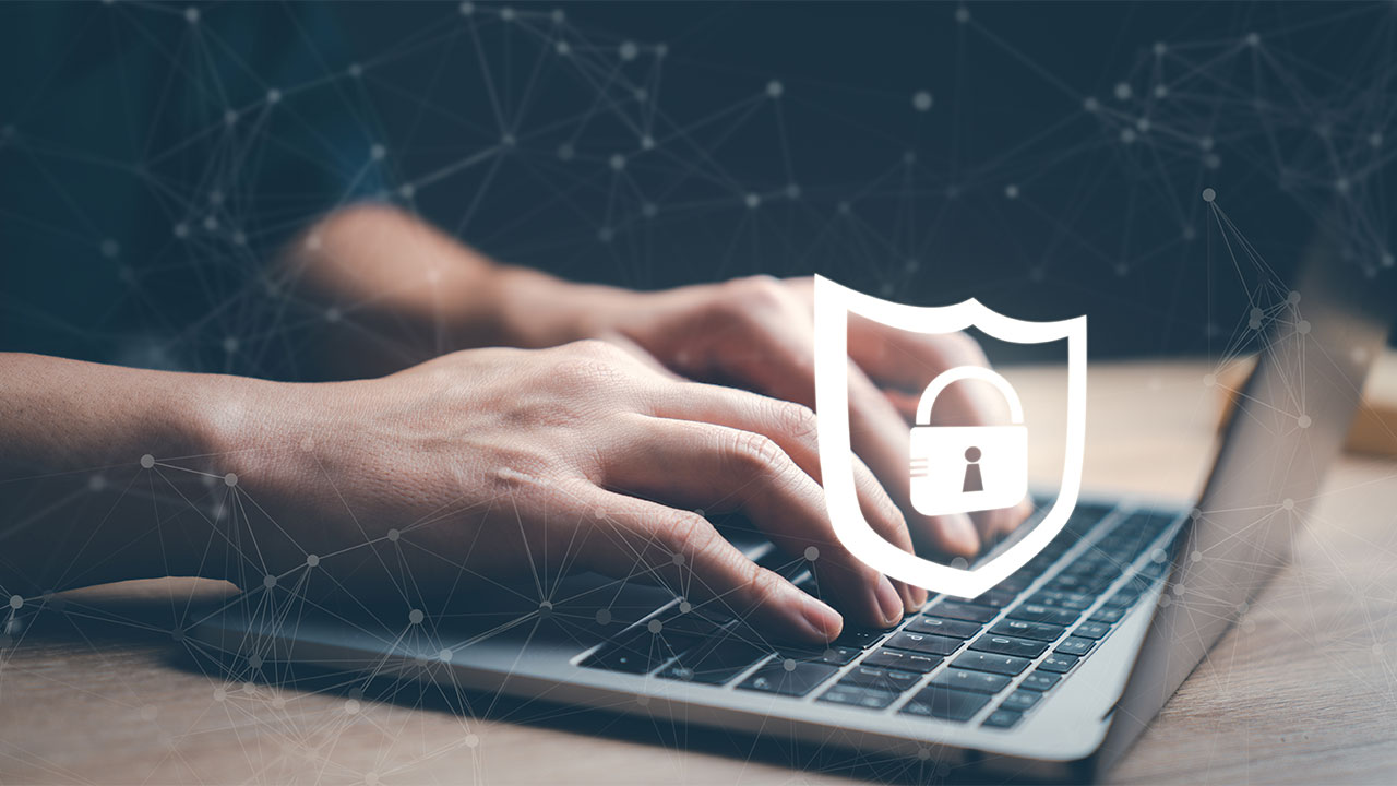 Zwei Hände tippen das Sicherheitspasswort in die Tastatur eines Laptops ein.